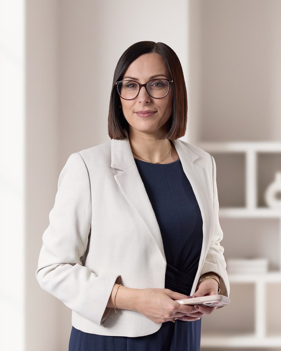 Maria Solazzo in hellem Blazer und dunklem Kleid in ihrem Büro