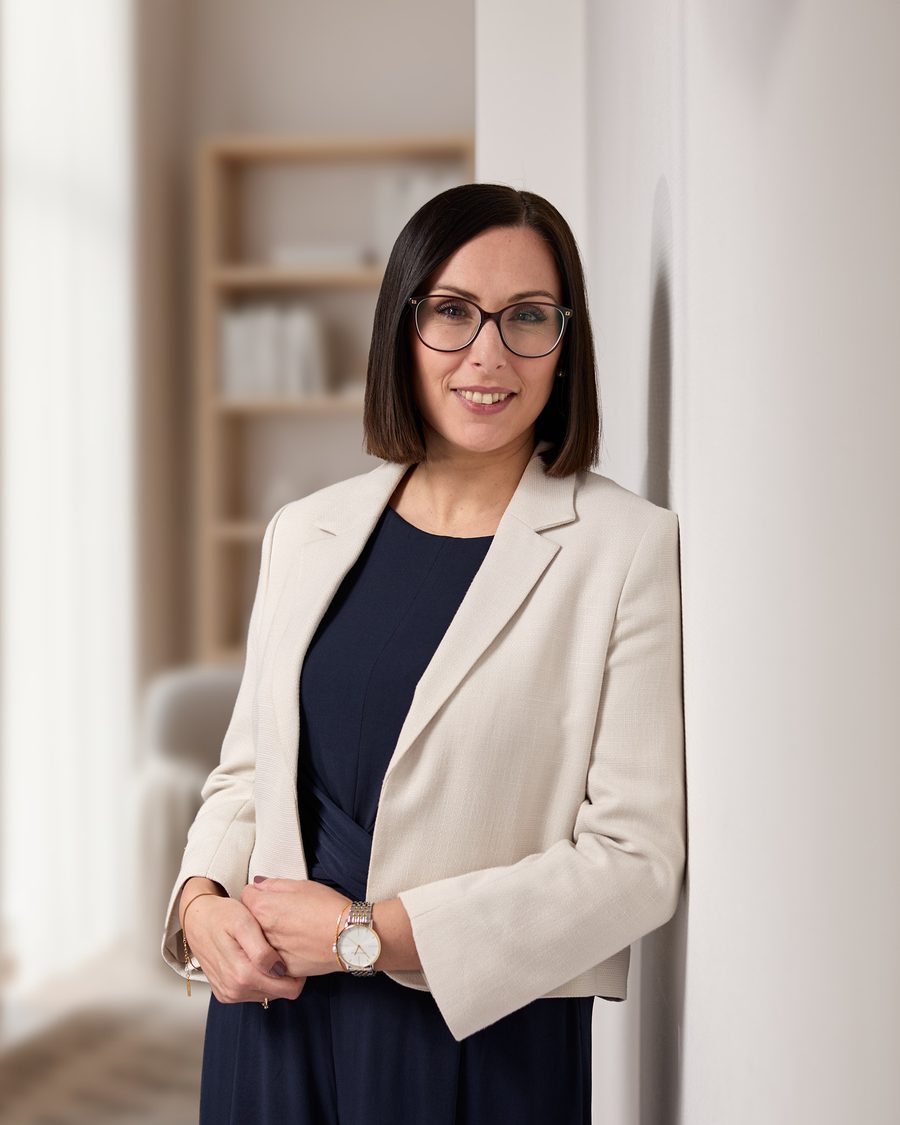 Maria Solazzo in hellem Blazer, an eine Wand gelehnt